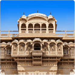 Ornate heritage sandstone palace with carved balconies and domes against blue sky