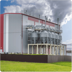 Industrial manufacturing facility with storage silos and red-panelled warehouse
